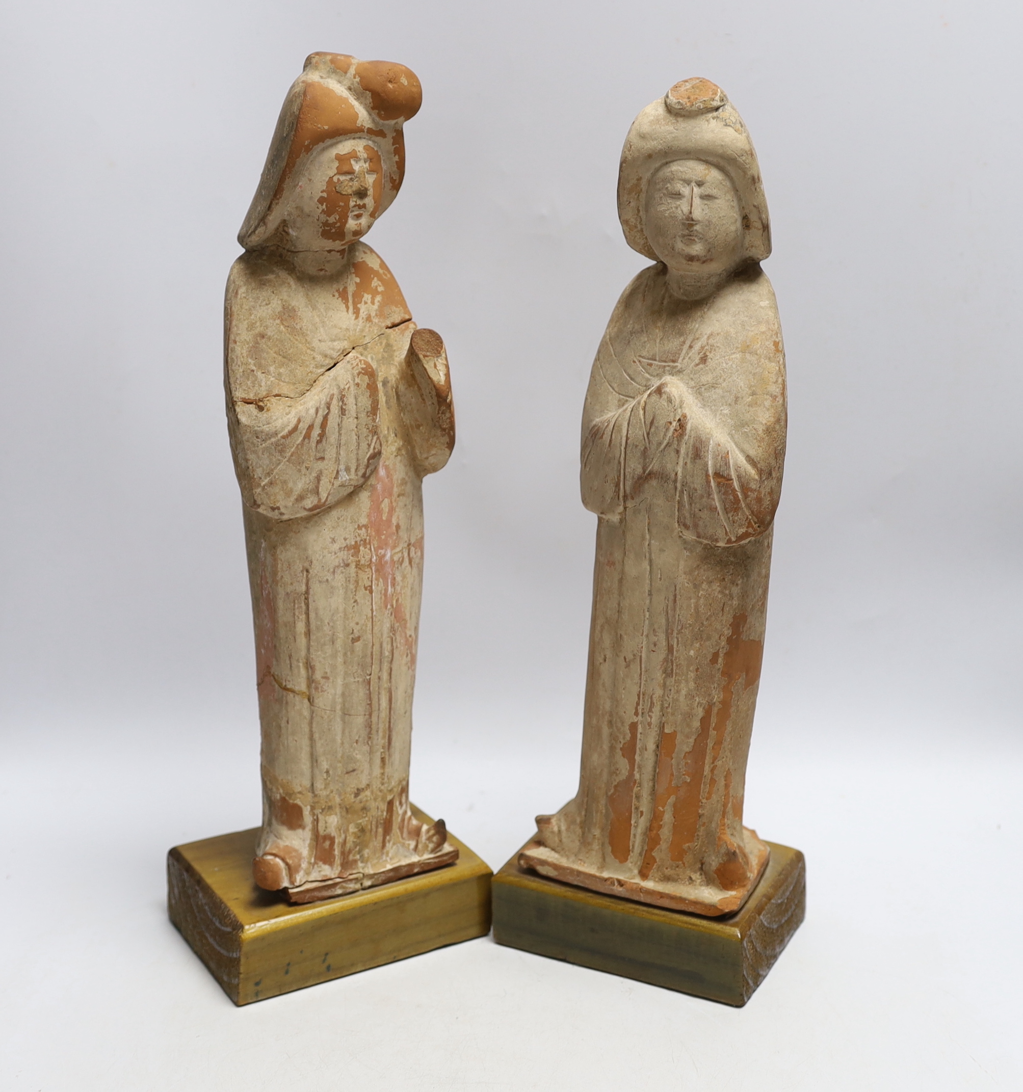 A pair of Chinese painted terracotta figures, possibly Tang Dynasty, on stained pine bases, 42cm high